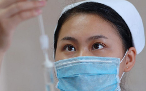 佩戴醫(yī)用口罩的護士給患者輸液